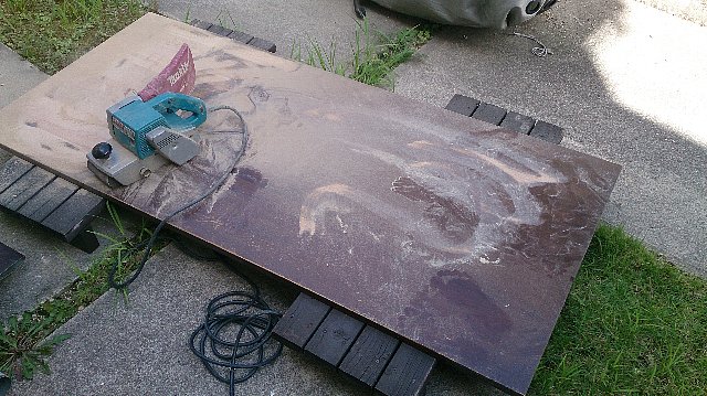 ベルトサンダーでダイニングテーブルの塗装を削る作業